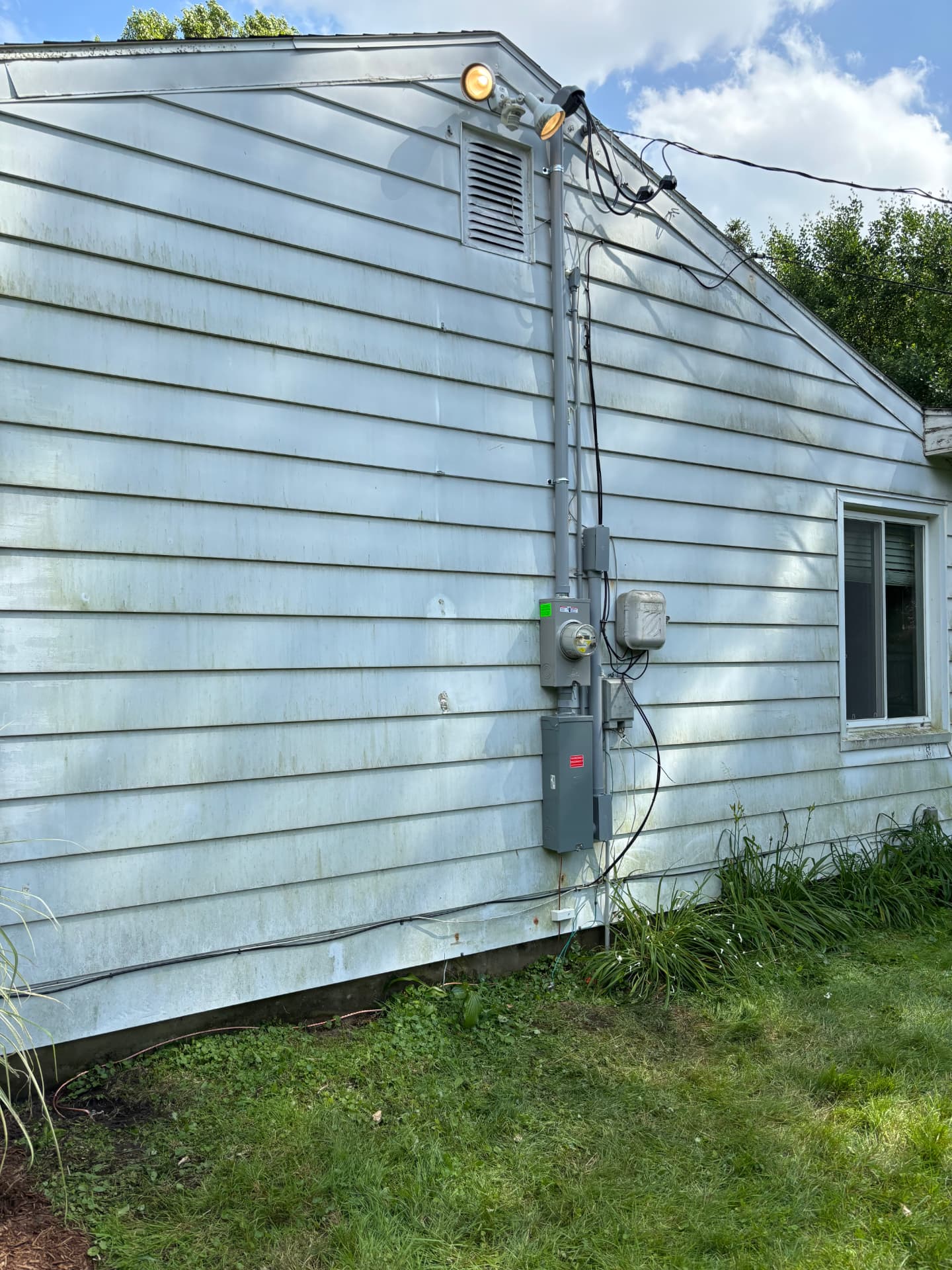 Newly installed electrical service mast, meter, and disconnect on a Lansing area home